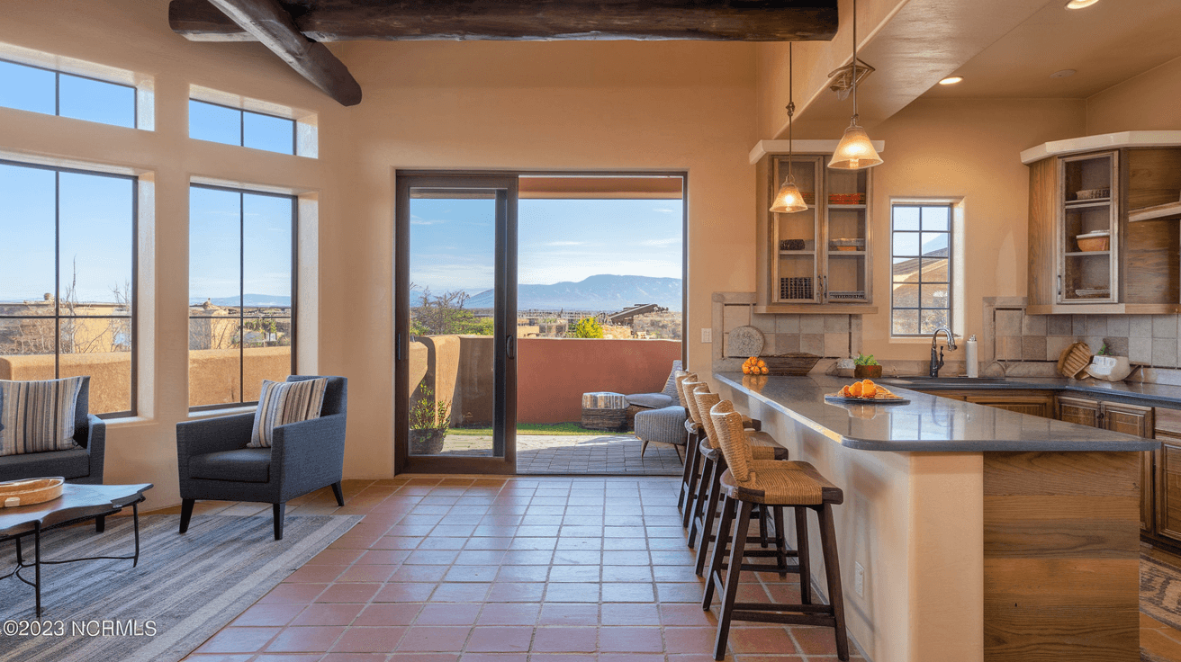 Interior of a staged Albuquerque townhome with Southwestern design accents, natural light flooding through large windows, a modern kitchen with quartz countertops, and mountain views visible through glass doors leading to a private patio