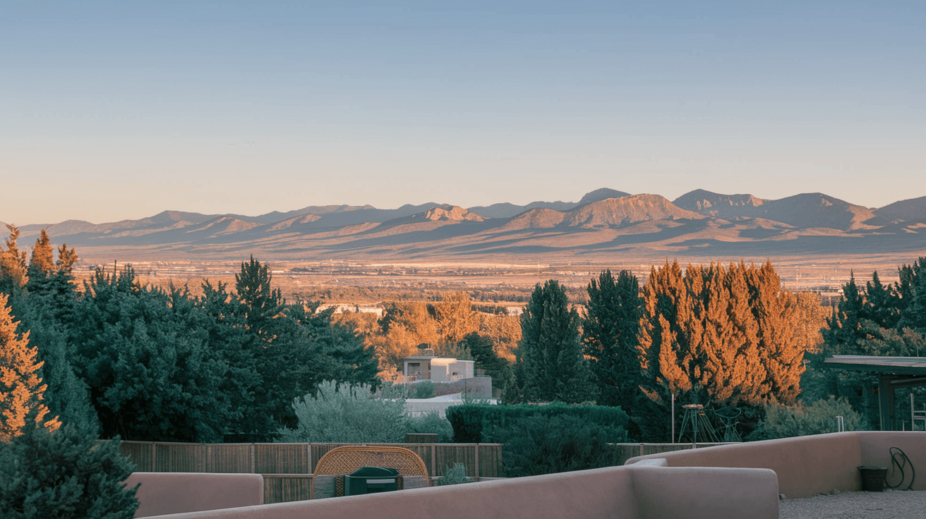 Elevated view from a Four Hills Albuquerque backyard showing the Rio Grande valley and West Mesa at golden hour, with the Sandia Mountains visible to the north